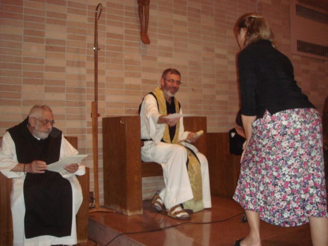 A priest handing a woman a certificate.