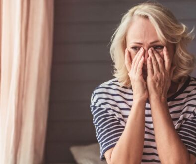 Distressed older woman covering her face with hands in frustration, illustrating emotional pain from being taken advantage of – how should Christians respond to people taking advantage of them with compassion, boundaries, and prayer instead of resentment.
