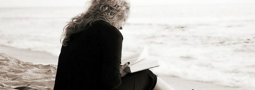 Woman with anxiety reading a book by the beach