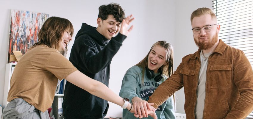 Group of young adults laughing and high-fiving while playing fun bible games for adults
