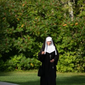 A medieval nun walking in the woods.