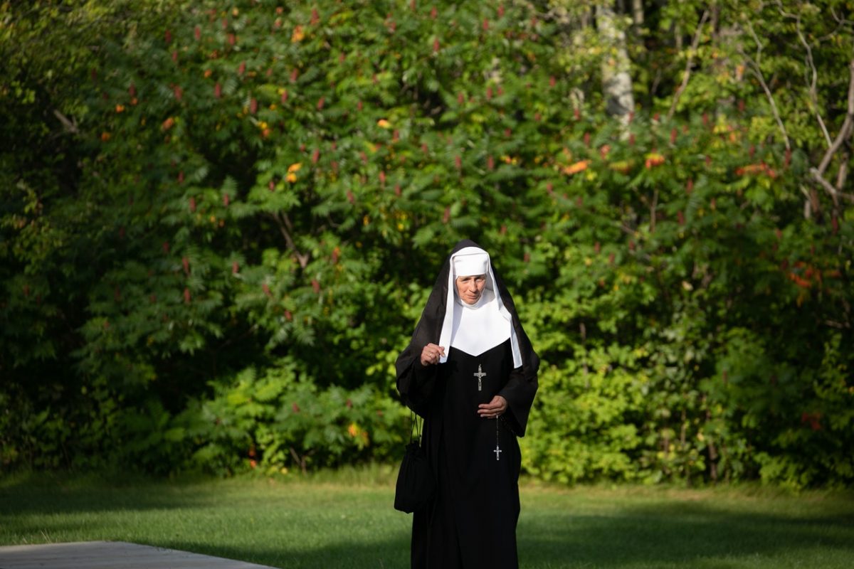 A medieval nun walking in the woods.