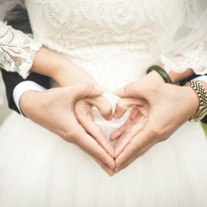 Husband and wife forming a heart sign with their hands
