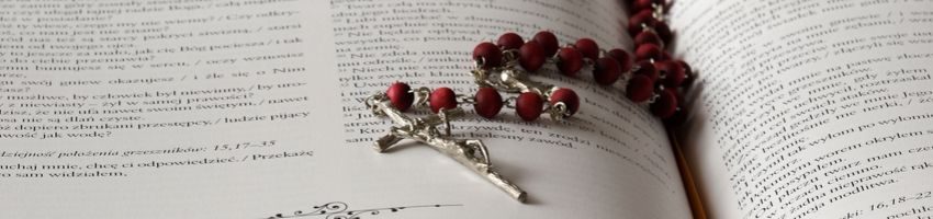 A rosary on top of the bible, two common symbols of the Catholic faith.