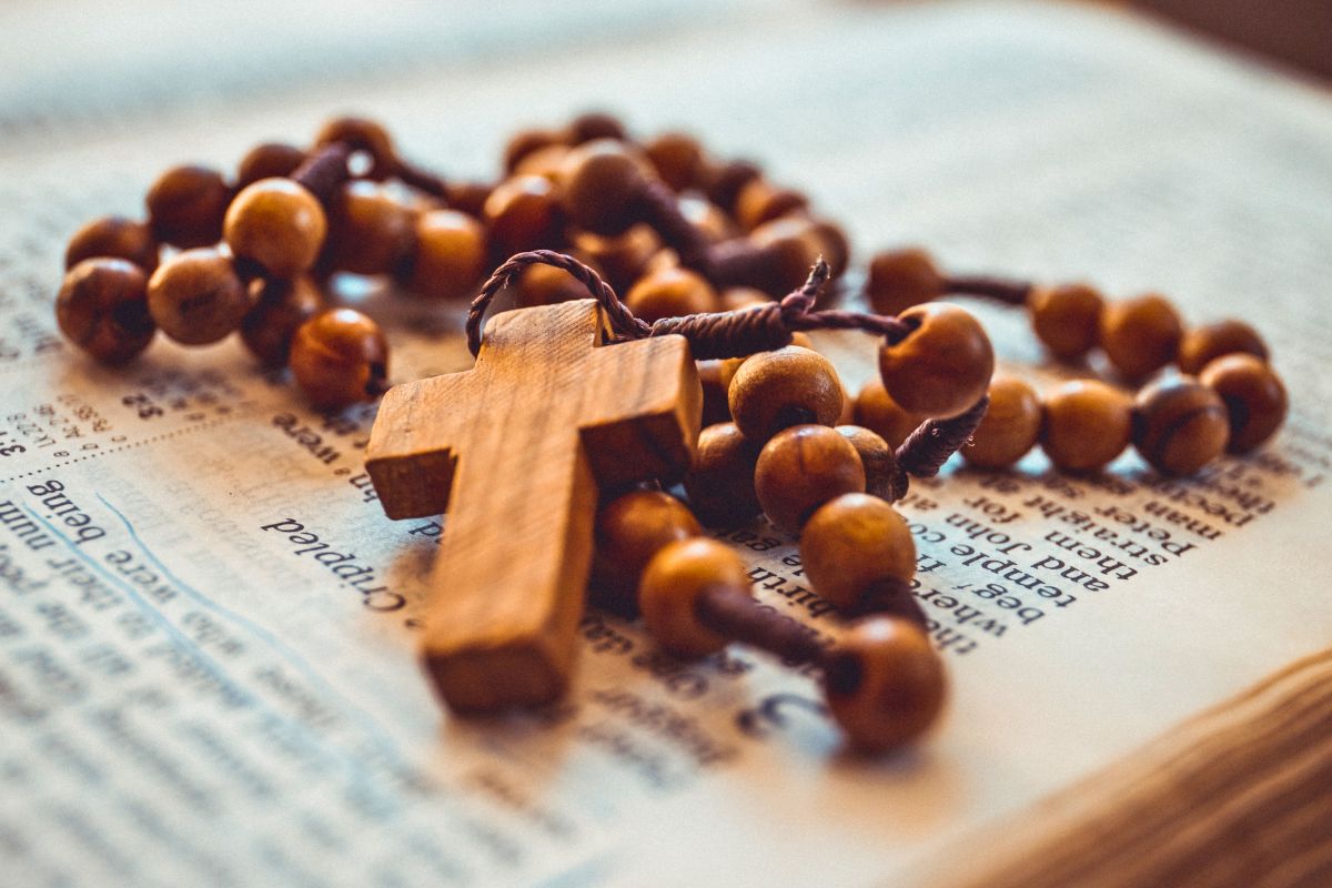 Praying the rosary in Latin represented by a rosary resting on top of a Bible, highlighting traditional Latin prayer devotion.