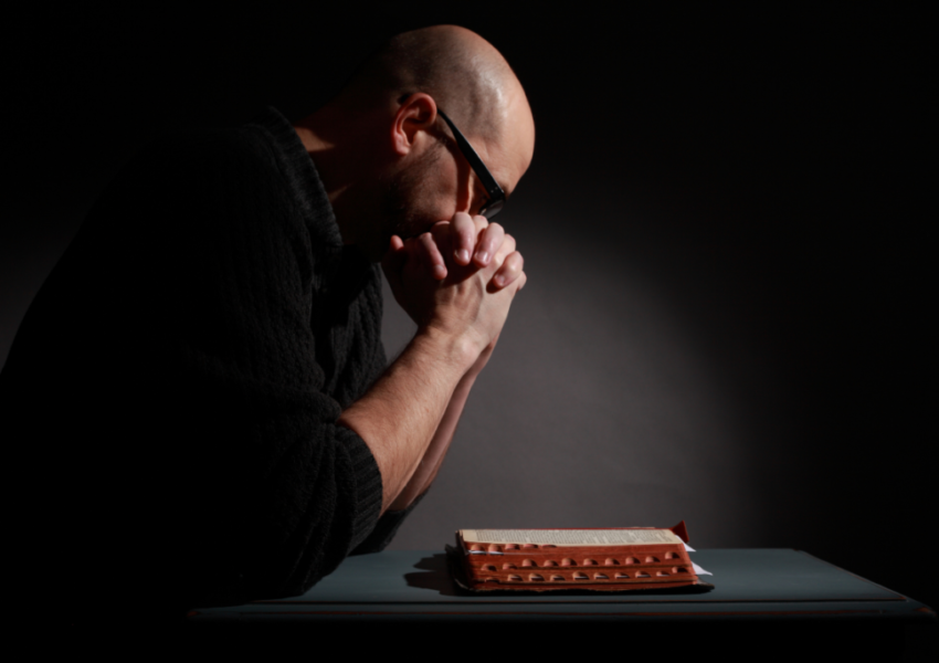 A man kneeling in front of the cross as a sign of repentance for the mortal sins he has committed.