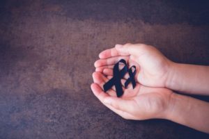 A person is holding a black ribbon representing death.