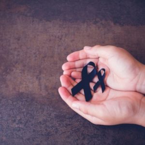 A person is holding a black ribbon representing death.