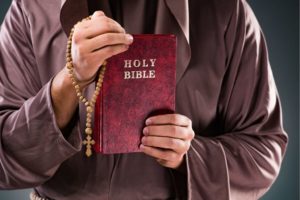 Priest holding the holy bible inside the church