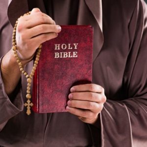 Priest holding the holy bible inside the church