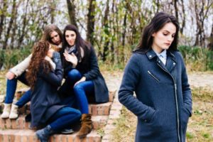 A group of teens at the back of a girl talking behind her back and slandering