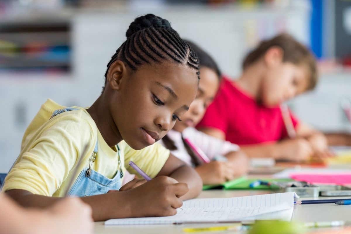 A school aged child studying in class.