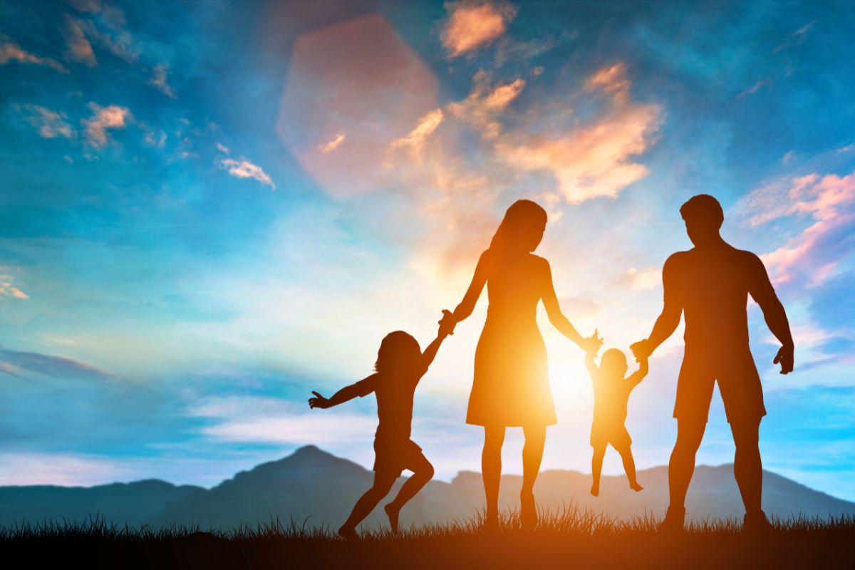 Joyful family silhouette at sunset with parents lifting their two young children, illustrating the love, discipline, and faith highlighted in bible verses about parenting responsibilities.