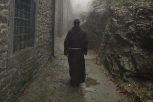 A catholic monk is walking down an alley.