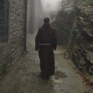 A catholic monk is walking down an alley.