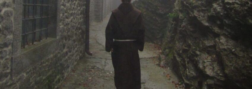 A catholic monk is walking down an alley.