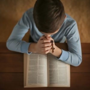 A Catholic child reading Bible verses for kids.