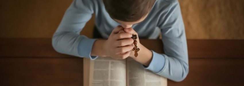 A Catholic child reading Bible verses for kids.