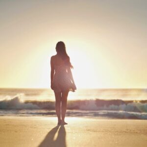 The woman stands in the front of the sunset while waiting for his love.
