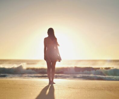 The woman stands in the front of the sunset while waiting for his love.