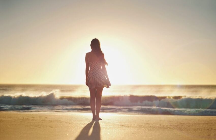 The woman stands in the front of the sunset while waiting for his love.