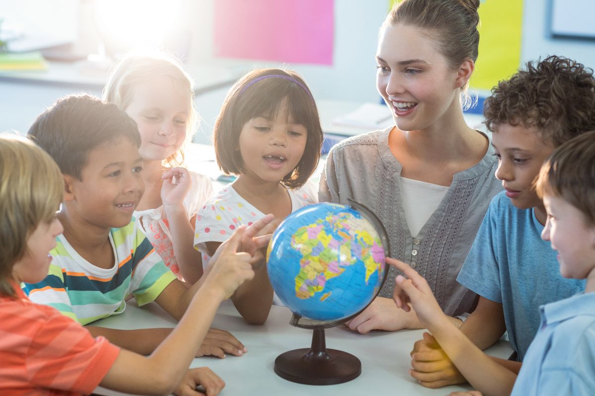 A teacher surrounded by her amused students.