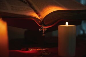 A Catholic prayer candle beside an open bible.