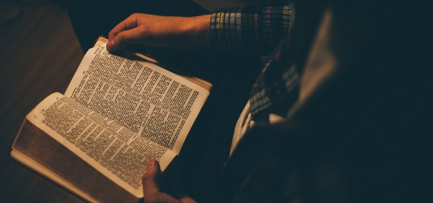 Someone reading a bible with little illumination.