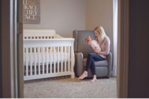 A mother cuddling her child while sitting inside the nursery.