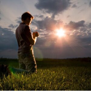 A man knelt on the grass to pray for a miracle to God.