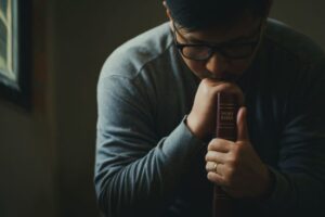 A man who is praying after reading scriptures for guidance.