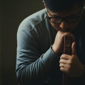 A man who is praying after reading scriptures for guidance.