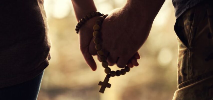 A couple holding their hand with the rosary.