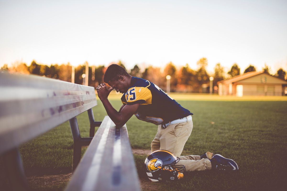 The athlete prays before the start of the game.
