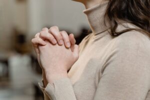 A woman saying her prayers for her husband