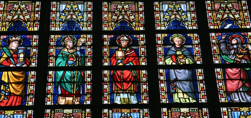 Colorful stained glass windows featuring various catholic saints names and figures