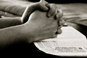 The man prays fervently after reading a book about Christian core values.