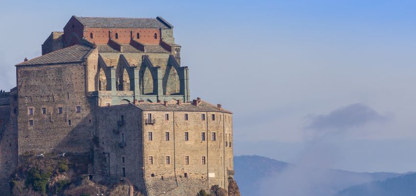 Sacre di San Michele is located near Turin, Italy. It's a captivating ancient Benedictine abbey meticulously built between 983 and 987. Perched on top of a majestic mountain, it offers panoramic views of the landscape and is a powerful symbol of its creators' dedication.