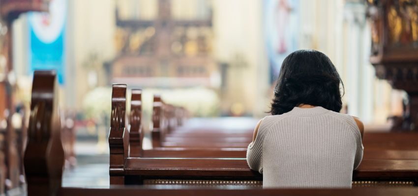 The woman prays solemnly at the church.