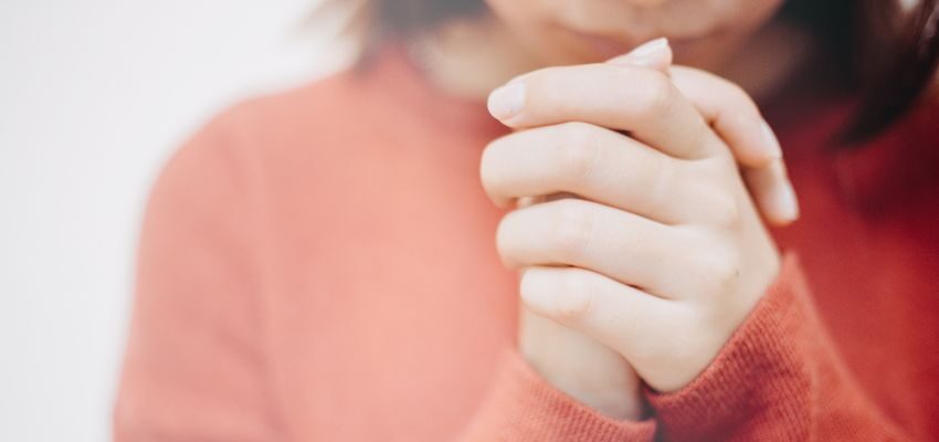 The woman prays solemnly after reading bible verses.