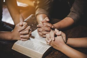 The group of people pray together after reading bible verses.