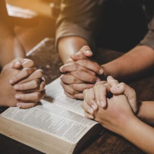 The group of people pray together after reading bible verses.