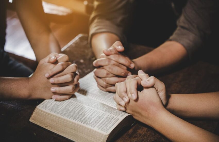 The group of people pray together after reading bible verses.