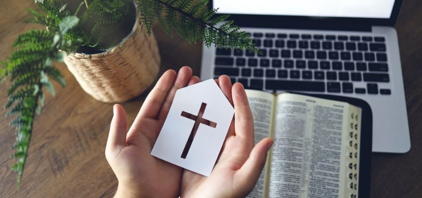 The woman holds an art with a cross at the center while watching Christian YouTubers.