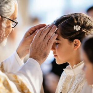 The bishop anoints a Catholic person with a small cross on their forehead in a Catholic confirmation ceremony.