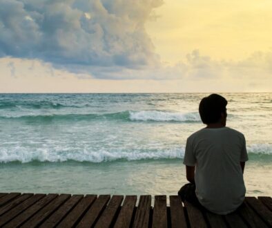 The man sitting in front of the sea feels alone.