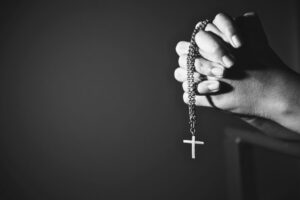 Hands holding a rosary with a cross, symbolizing faith and miracle prayer.