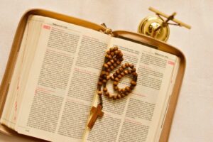 Open Bible with rosary beads resting on short bible verses pages