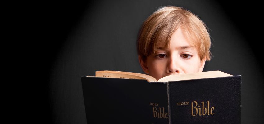 Young boy deeply focused while reading short bible verses from the Holy Bible