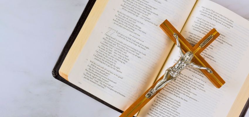 Open Holy Bible with a wooden crucifix resting on the pages, ideal for bible verse Sunday inspiration